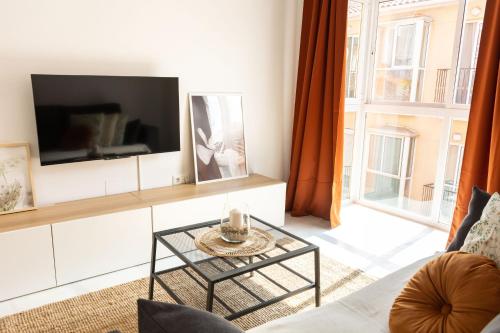 uma sala de estar com uma televisão e uma mesa de centro em La Besana Home em Málaga