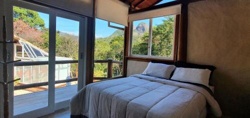 Schlafzimmer mit einem Bett vor einem großen Fenster in der Unterkunft Casa Maria Comprida Araras, serviço incluído, 5 quartos, piscina e área gourmet in Petrópolis