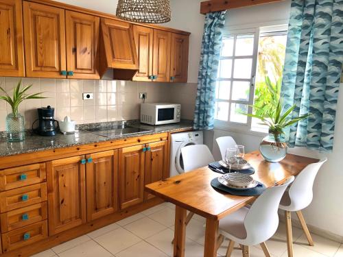 a kitchen with wooden cabinets and a wooden table with chairs at Casa La Galera (Playa a 50 metros) in Corralejo