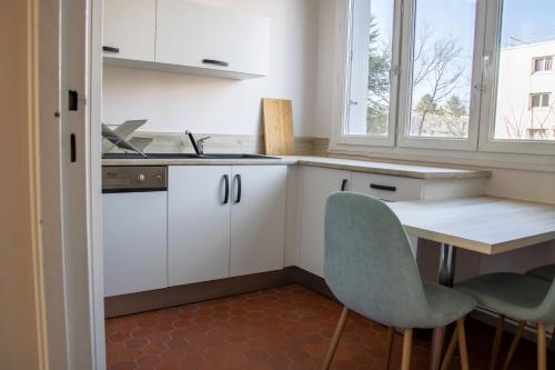 - une cuisine avec des placards blancs, une table et des chaises dans l'établissement La Fabrique Paloise, à Pau