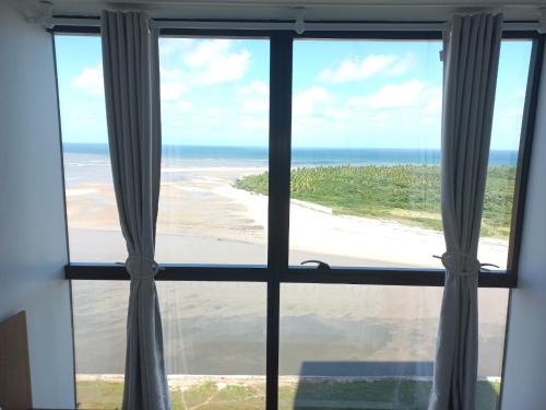 a view of a beach from a window at FLAT BEIRA MAR BARRA DE JANGADA ANDAR ALTO JABOATão in Recife