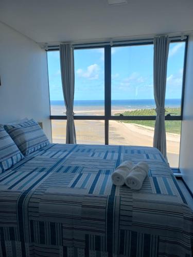 a bedroom with a bed and a view of the beach at FLAT BEIRA MAR BARRA DE JANGADA ANDAR ALTO JABOATão in Recife