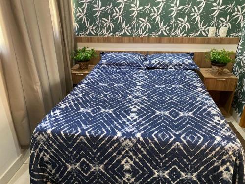a bed with a blue and white comforter in a bedroom at Everest Flat Service - Apartamento 301 in Caldas Novas