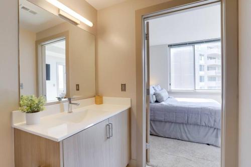 a bathroom with a sink and a mirror and a bed at Amazing 2BR Condo At Crystal City With Rooftop in Arlington