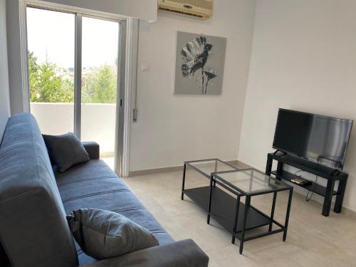 a living room with a blue couch and a tv at 1-bedroom apartment with view in Limassol