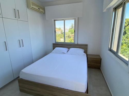 um quarto com uma cama branca e 2 janelas em 1-bedroom apartment with view em Limassol