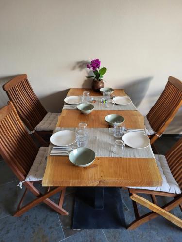 a wooden table with plates and glasses on it at Villa Alva Guest House in Coja