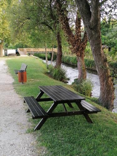 a picnic table and two benches next to a river at Villa Alva Guest House in Coja