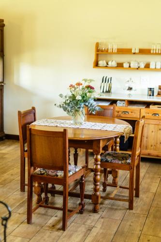 a kitchen table with a vase of flowers on it at Baris Guesthouse in Clarens