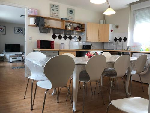 - une cuisine avec une table et des chaises blanches dans l'établissement la Discrète, à Berck-sur-Mer