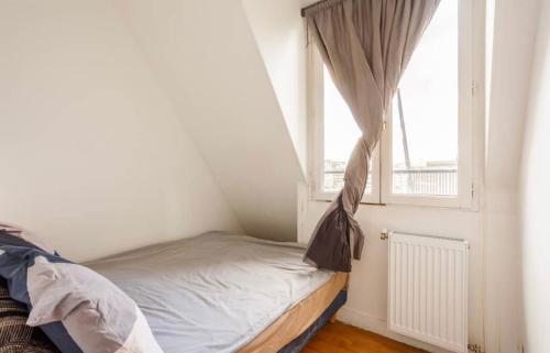 a small bed in a room with a window at Beautiful apartment with a view of Eiffel Tower in center Paris in Paris