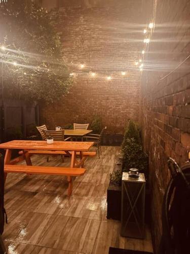 a patio with a wooden table and chairs and a brick wall at 1850s historic Row House 7min train to NYC with private backyard in Jersey City