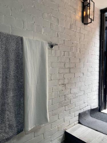 a bathroom with a white brick wall and a towel at 1850s historic Row House 7min train to NYC with private backyard in Jersey City