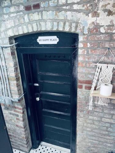 a black door in a brick wall with a sign on it at 1850s historic Row House 7min train to NYC with private backyard in Jersey City