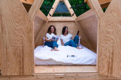 2 femmes assises sur un lit dans une maison à colombages dans l'établissement SKY HOUSE EXPERIENCE, à Salmore