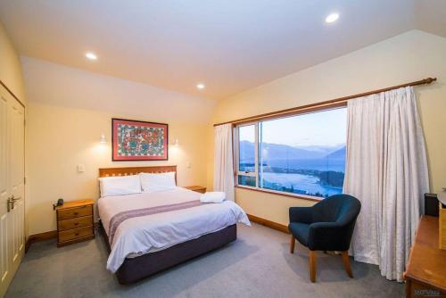 een slaapkamer met een bed en een groot raam bij Nyumbani - Elevated Lake and Mountain Views in Queenstown