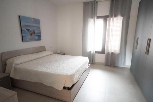 a white bedroom with a bed and a window at SGM CASA VACANZE in Masainas