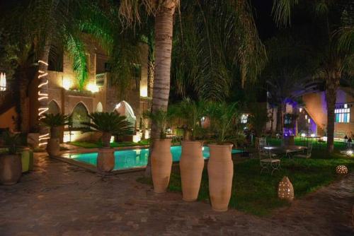 un complexe avec une piscine et des palmiers la nuit dans l'établissement Dar Riad Niama, à Taroudant