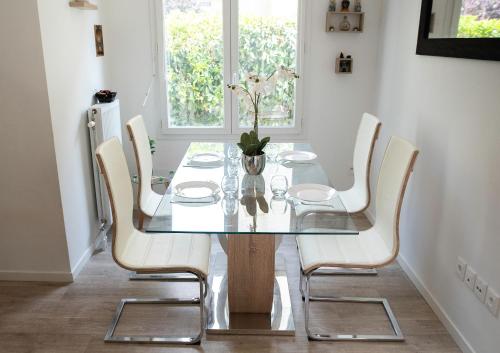 芒特拉若利的住宿－T3 bord de Seine,proche centre ville,parking privé，一间设有玻璃桌和白色椅子的用餐室
