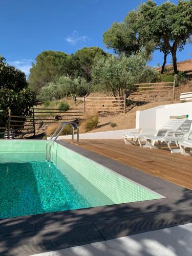 a swimming pool with chairs and trees in the background at Monte do Pereiro in Santiago do Cacém