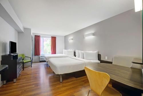 Habitación de hotel con 2 camas y mesa en Motel 6 Airdrie, en Airdrie