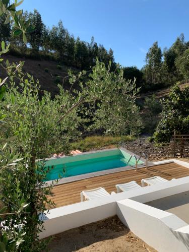 a swimming pool on a wooden deck with white chairs at Monte do Pereiro in Santiago do Cacém