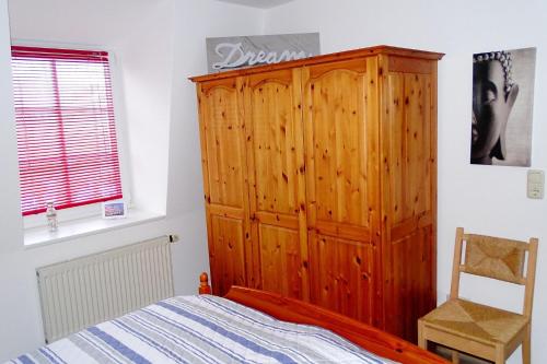 a bedroom with a wooden cabinet next to a bed at Strandstr_55 Wohng_5 in Zingst