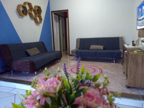 a living room with two couches and flowers in a room at Harmonia Haus in Blumenau
