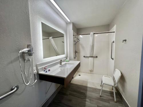 a bathroom with a sink and a shower and a mirror at Days Inn by Wyndham Suites Fredericksburg in Fredericksburg