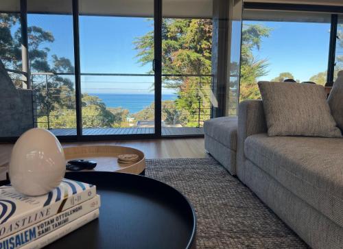 a living room with a couch and a table at Architect designed 4 bedroom with ocean views from every room in Lorne