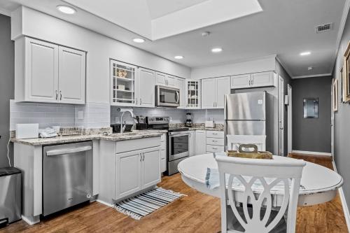 a kitchen with white cabinets and a table and a refrigerator at Dunescape Villas 346 in Atlantic Beach