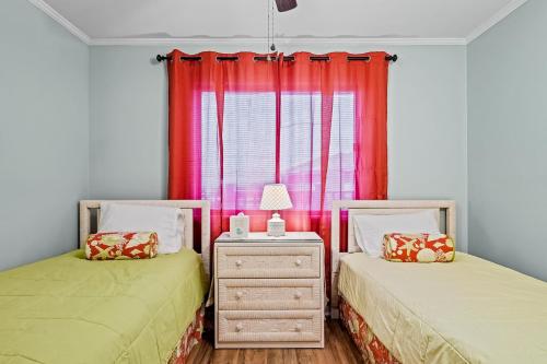 a bedroom with two beds and a dresser and a window at Dunescape Villas 346 in Atlantic Beach