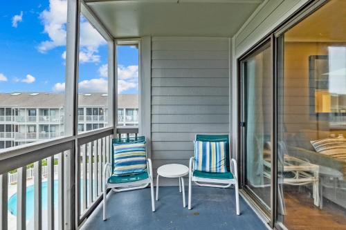 a balcony with two chairs and a table and a pool at Dunescape Villas 346 in Atlantic Beach