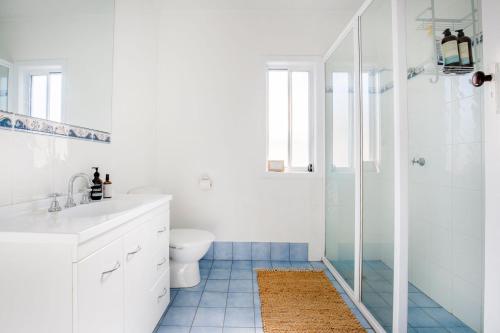 a white bathroom with a toilet and a shower at Fishery Road Cottage Pet Friendly 2 Mins Walk to Beach in Currarong