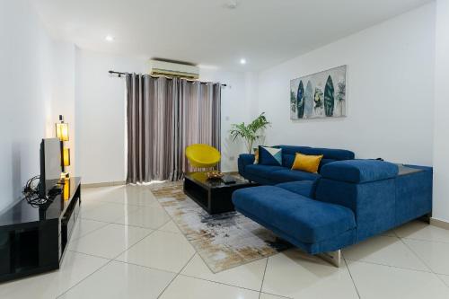 a living room with a blue couch and a tv at The Avery Apartments at Clifton Place, East Legon in Accra