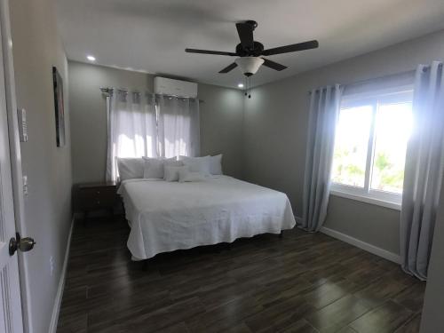 - une chambre avec un lit blanc et un ventilateur de plafond dans l'établissement Single-Family Home With Gated Tropical Yard, à Roatán