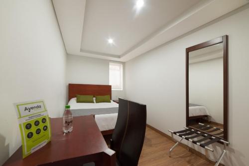 1 dormitorio con cama, mesa y espejo en Ayenda 1043 Kafir, en Bogotá
