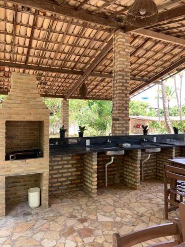 an outdoor patio with a stone fireplace and a wooden roof at Chalés Porto do Sol in Pipa