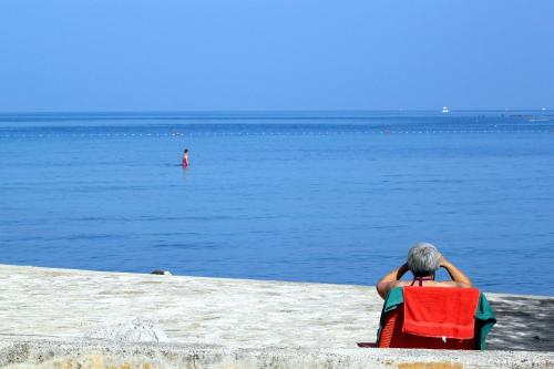 a man sitting in a chair on the beach looking at the water at Apartments with WiFi Groznjan, Central Istria - Sredisnja Istra - 7038 in Grožnjan