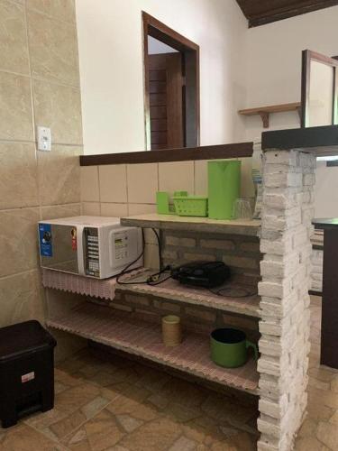 a kitchen with a microwave sitting on a shelf at Chalés Porto do Sol in Pipa