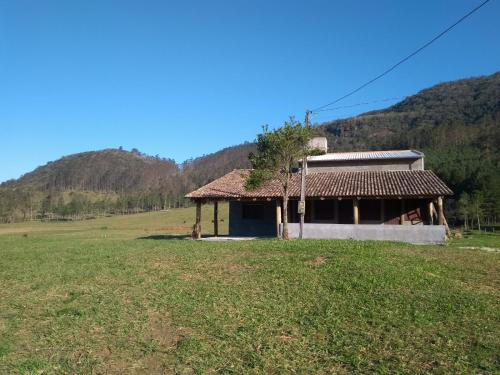 uma pequena casa num campo com uma montanha em Hostel e Pousada Vale Mirante da Rocha em Timbe do Sul