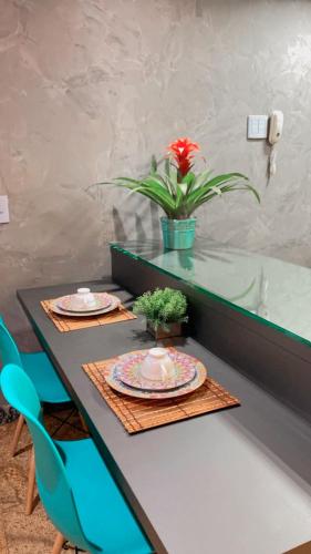 a table with two plates and a potted plant on it at Lindo Apart Lake Side com banheira in Brasilia