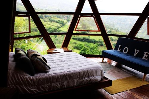 a bedroom with a bed in a room with a large window at Glamping Corazón del Molino in Ubaque