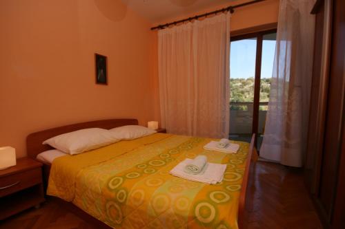 a bedroom with a bed with towels and a window at Apartments and rooms by the sea Jakisnica, Pag - 4160 in Lun