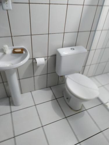 a white bathroom with a toilet and a sink at Pousada do guariba in Santa Teresa