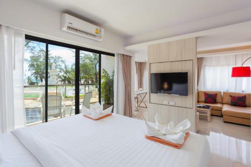 a white bedroom with a large white bed and a tv at Coral Inn in Karon Beach