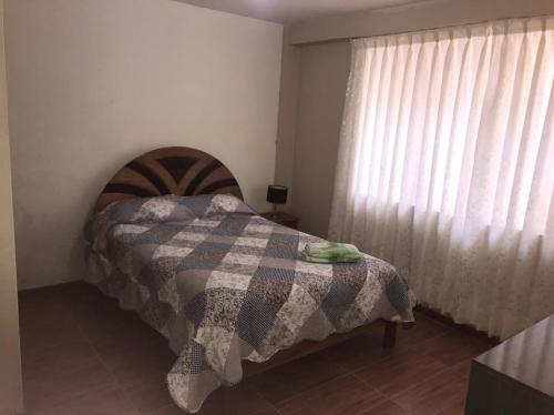 1 dormitorio con 1 cama con manta y ventana en Departamentos Camino Real incluye garaje, en Cusco