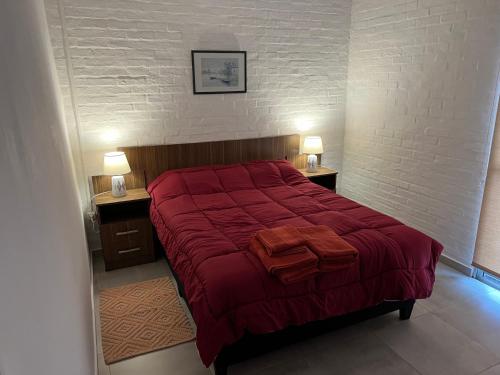 - une chambre avec un grand lit rouge et deux lampes dans l'établissement Apart del Este 2, à Paysandú