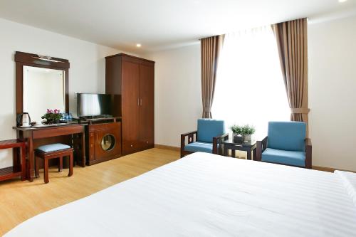 a bedroom with a bed and two chairs and a desk at ALUNA Ben Thanh Hotel in Ho Chi Minh City