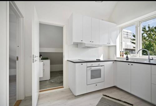 eine weiße Küche mit weißen Schränken und einem Waschbecken in der Unterkunft A Place To Stay Stavanger, apartment 3 in Stavanger